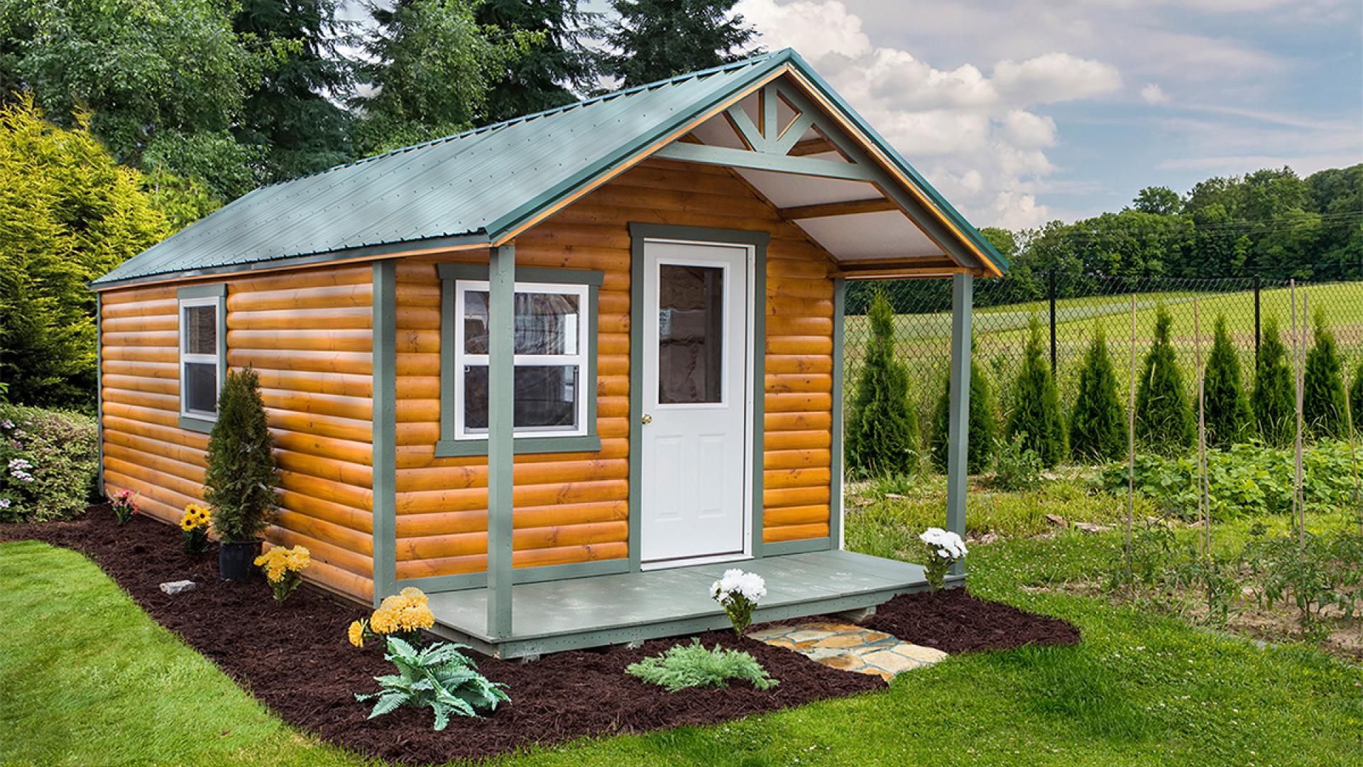 Signature hunter cabin with brown half log siding, a front porch, windows, a white front door with a window, and a metal roof.